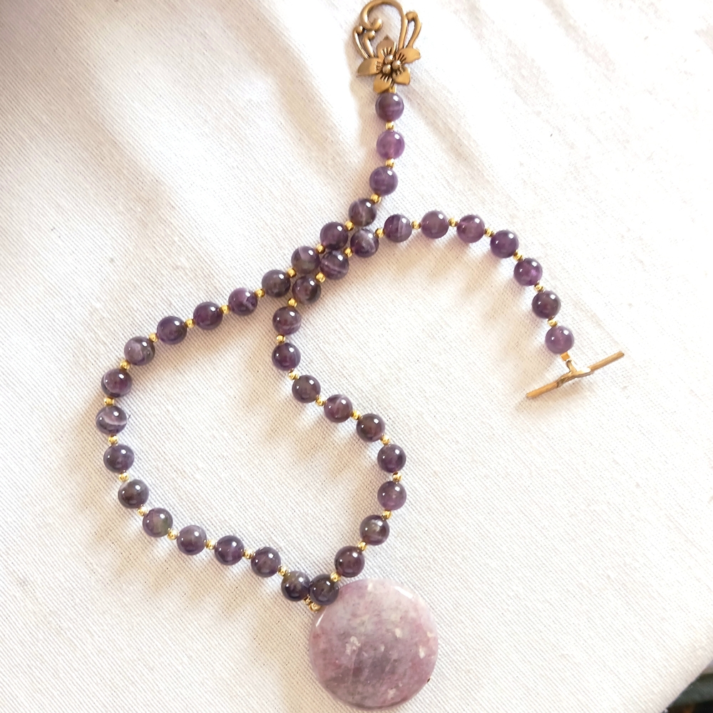 Amethyst Beaded Necklace with Floral Tibetan-Style Clasp. 17” sits on collar b